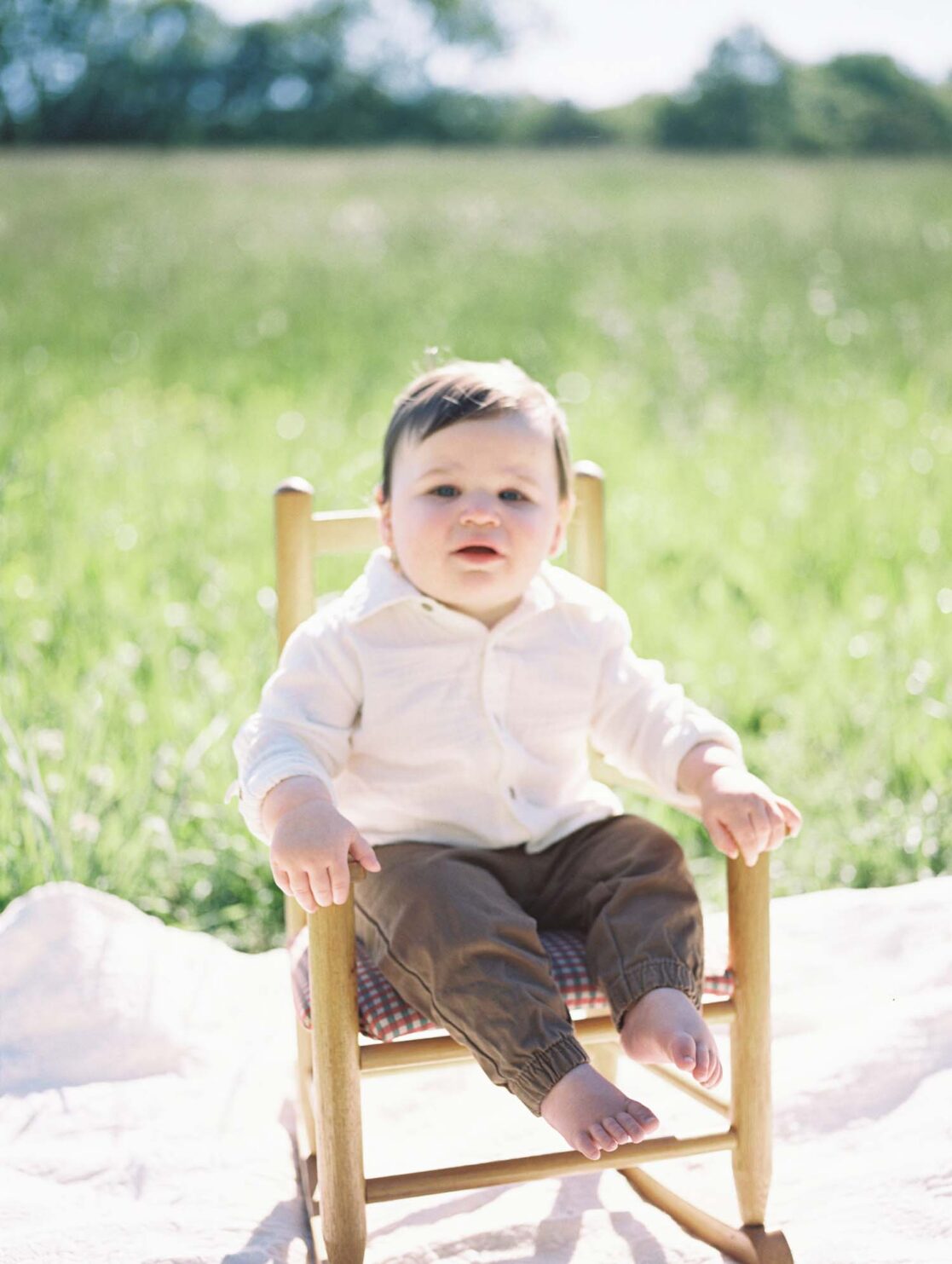 Photo one year old baby boy sitting in a rocking chair in a grassy field by Richmond baby photographer Jacqueline Aimee Portraits