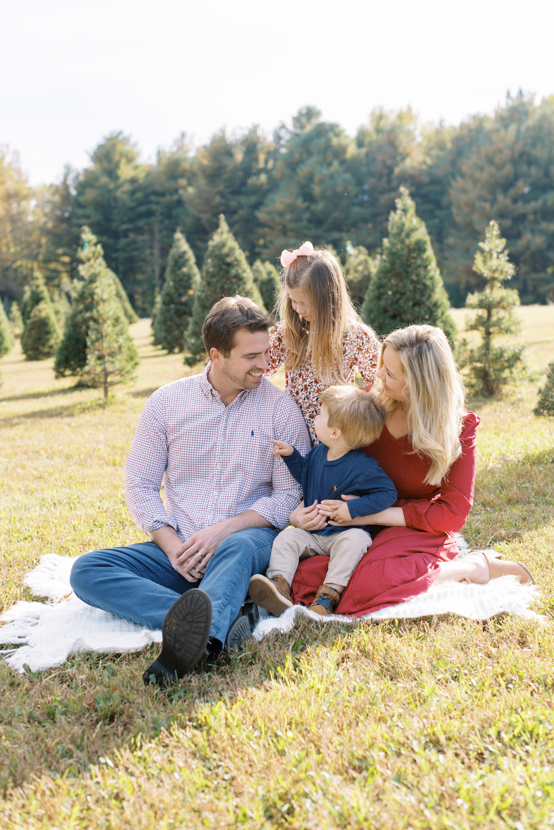 mother and father posed with son and daughter for christmas card photo at christmas tree farm