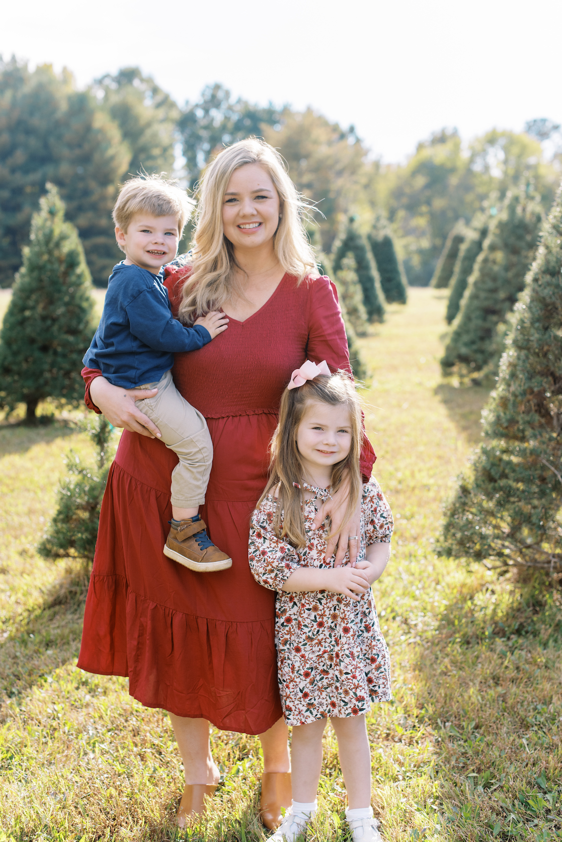 mother posed with son and daughter for christmas card photo at christmas tree farm