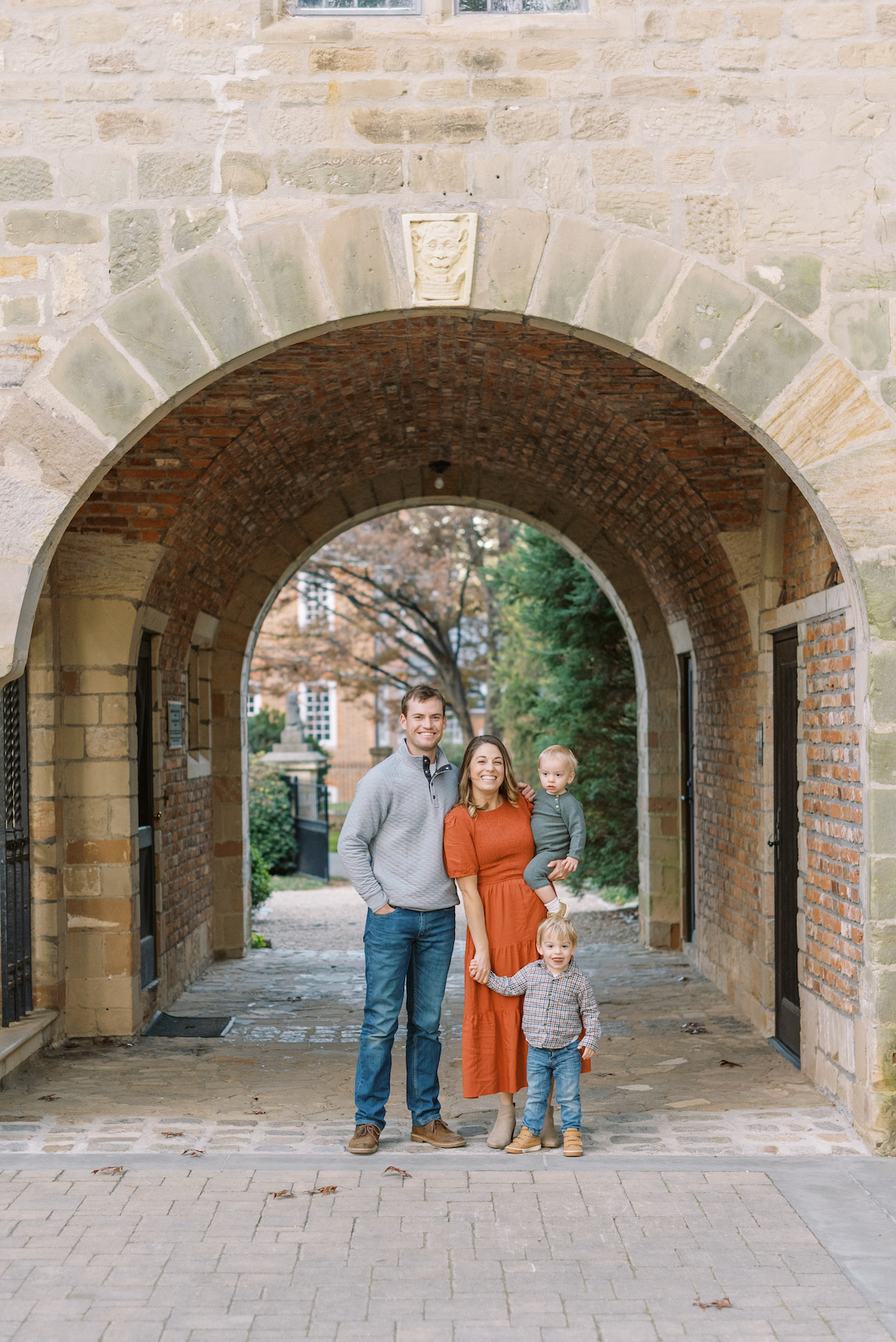 family of four portraits outside under arch