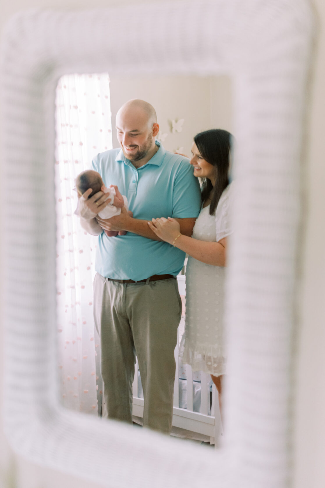 creative portrait of parents holding newborn in mirror