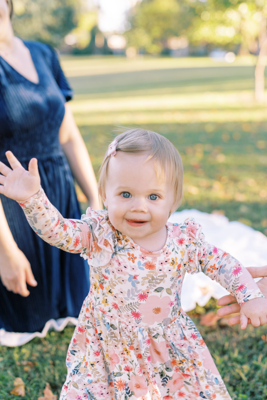 Photo of a toddler girl practicing her wave during their richmond fall mini session with jacqueline aimee portraits