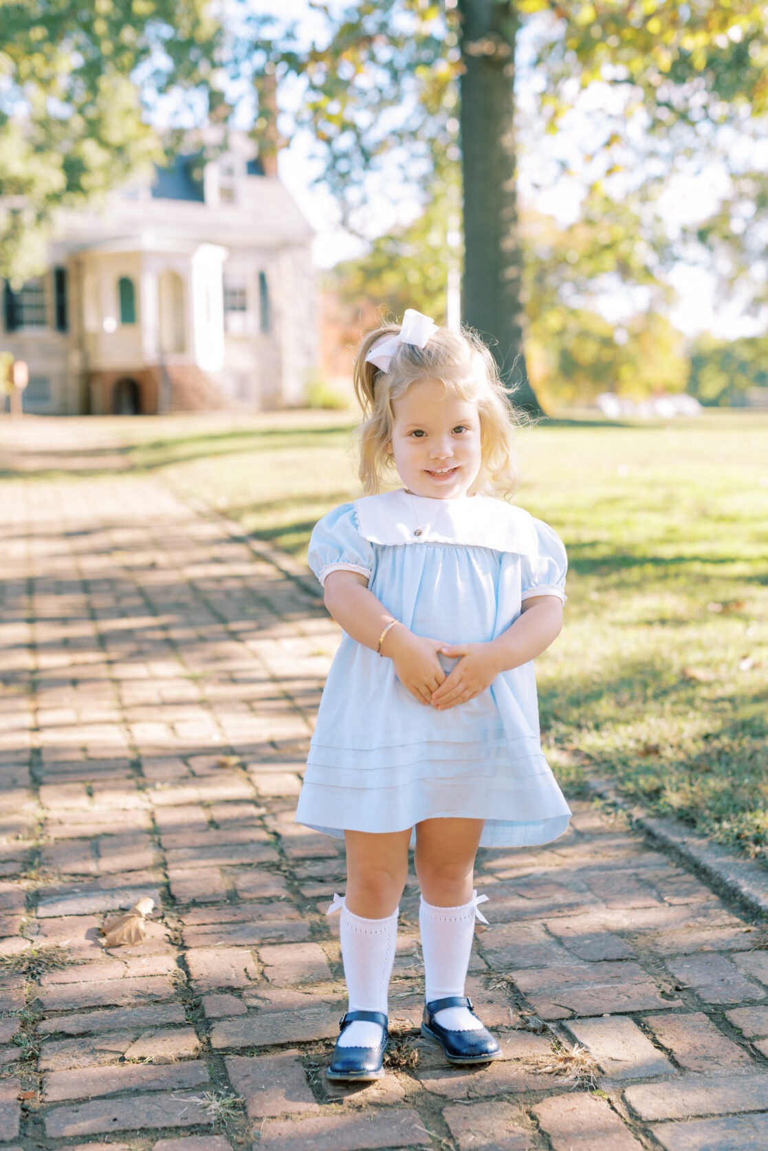 Photo of a toddler girl smiling amongst the fall foliage during their richmond fall mini session with jacqueline aimee portraits