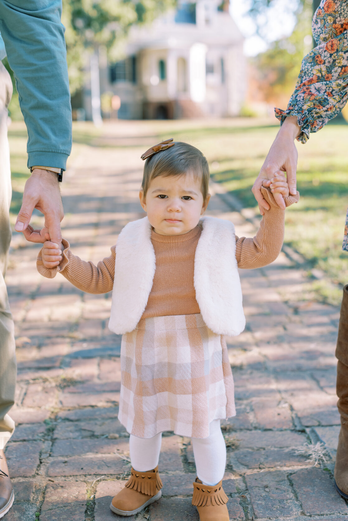 Photo of a toddler girl holding her parents' hands amongst the fall foliage during their richmond fall mini session with jacqueline aimee portraits