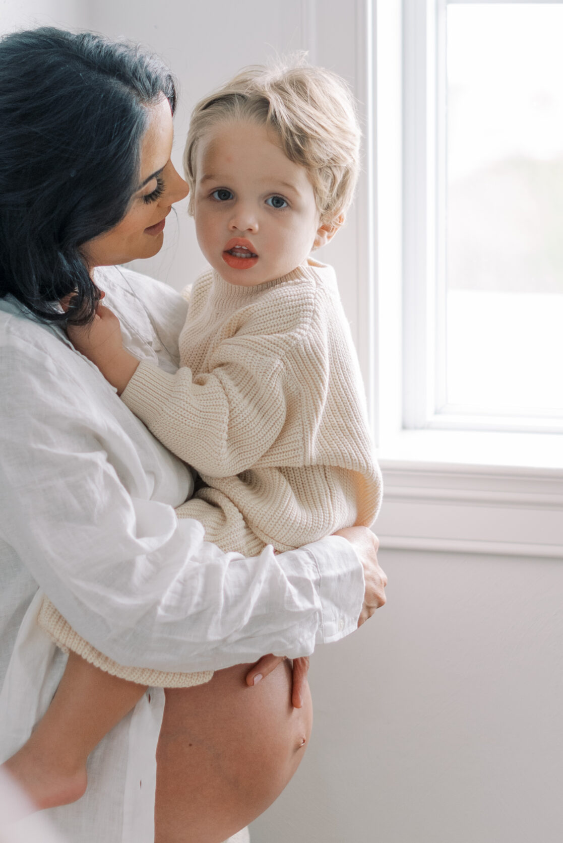 Richmond Birth Doula | Photo of a pregnant mom holding her older toddler son. The little boy is looking at the camera while his mom looks at him and nuzzles his temple by Richmond maternity photographer Jacqueline Aimee Portraits