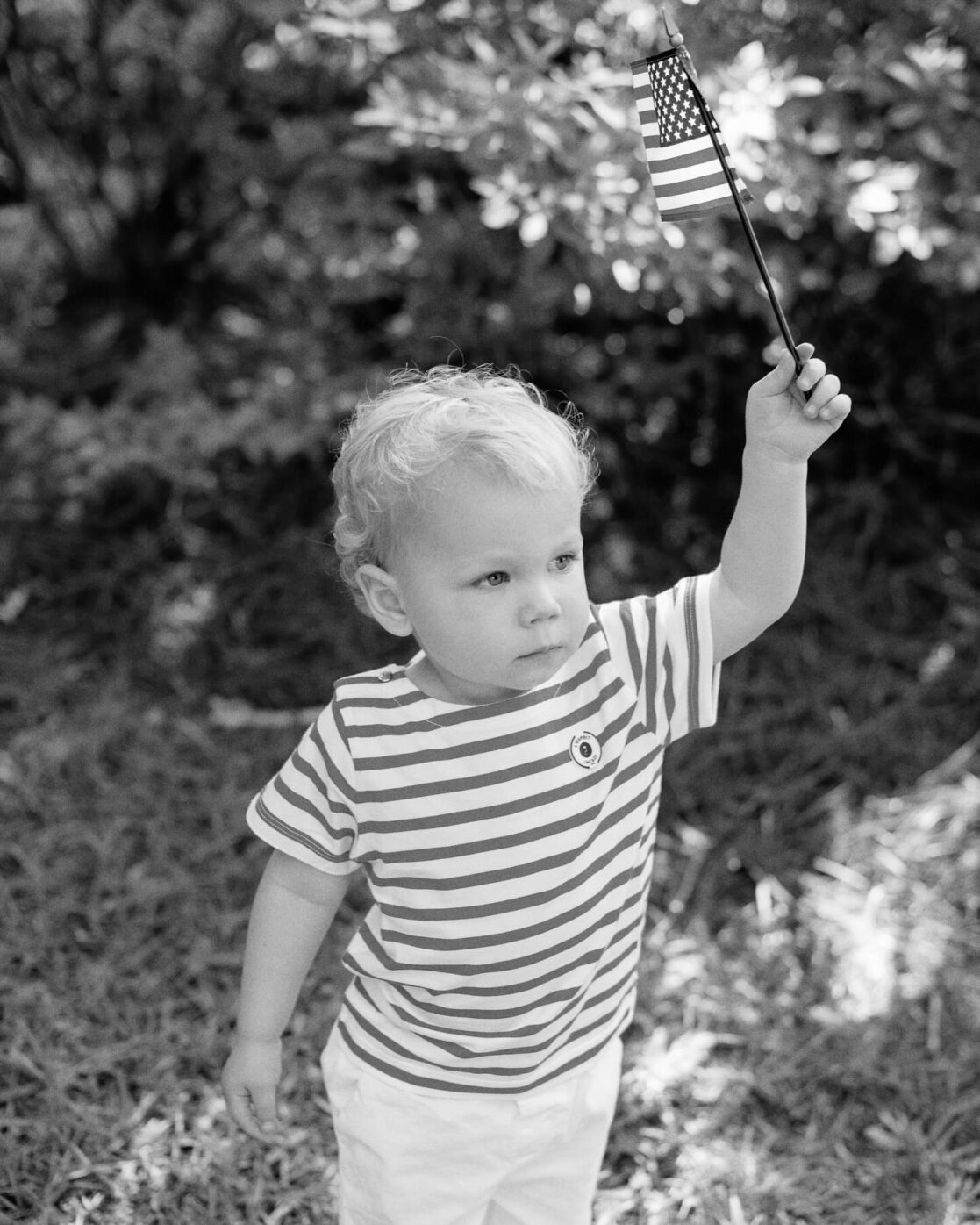 4th of July events in Richmond | Black and white photo of a little boy holding up an American flag by Richmond family photographer Jacqueline Aimee Portraits