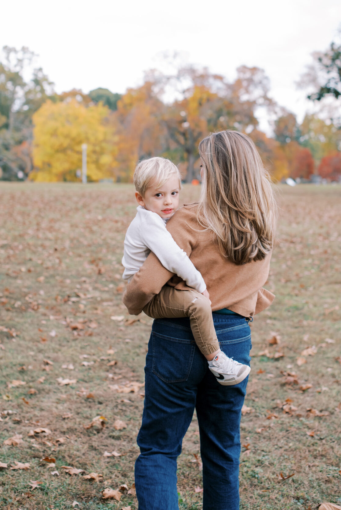 Richmond VA Fall Family Photos | A mother walks with her young son amongst the fall leaves