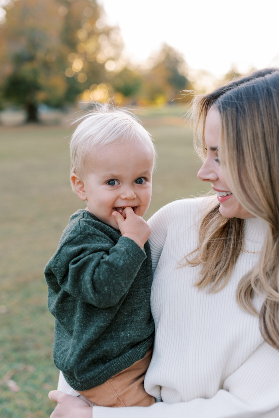 Richmond VA Fall Family Photos | A mother admires her baby boy, posing before golden, leaves in a Richmond park during autumn