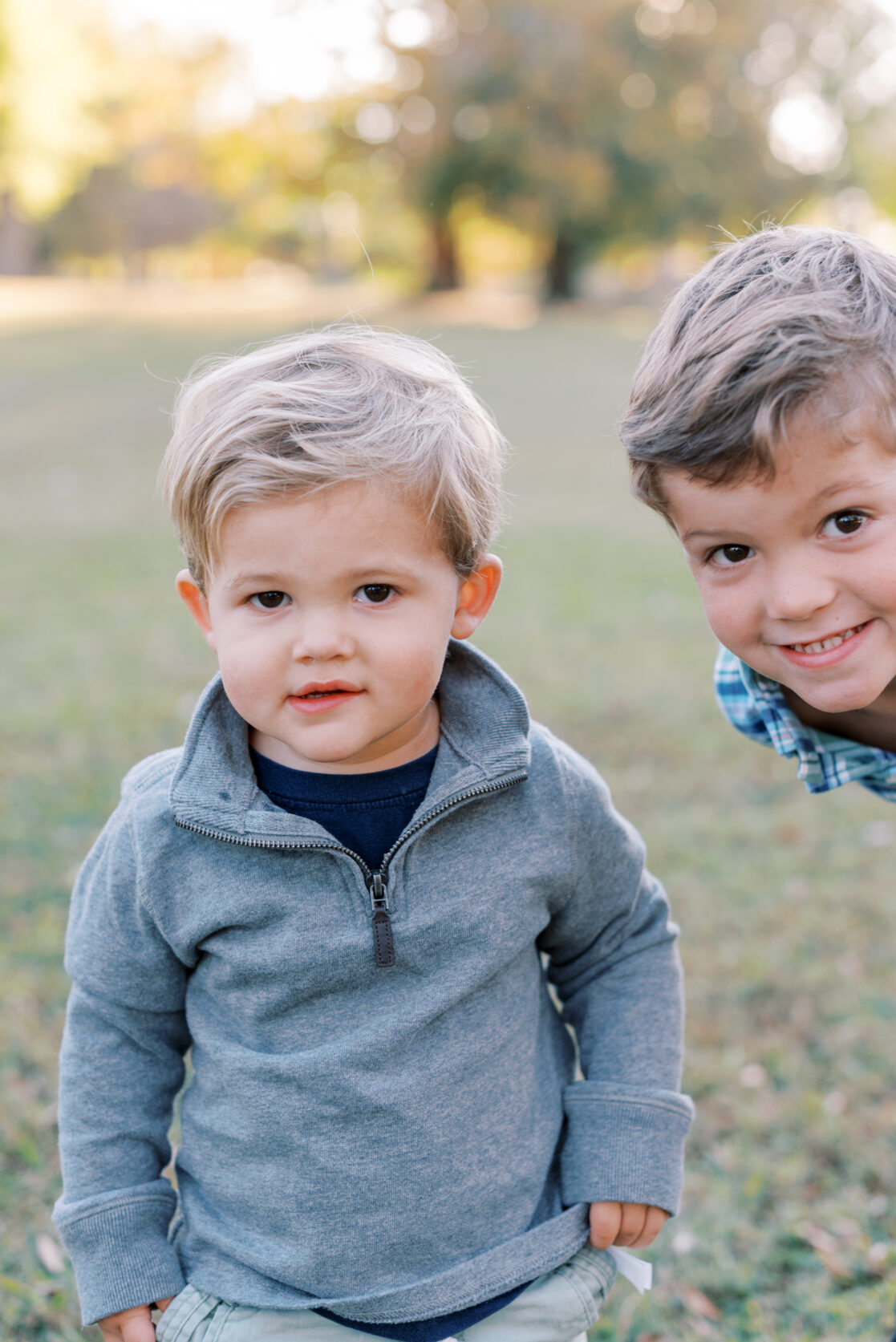 Richmond VA Fall Family Photos | Children siblings stand together for a photo in a park, surrounded by golden autumn leaves at sunset