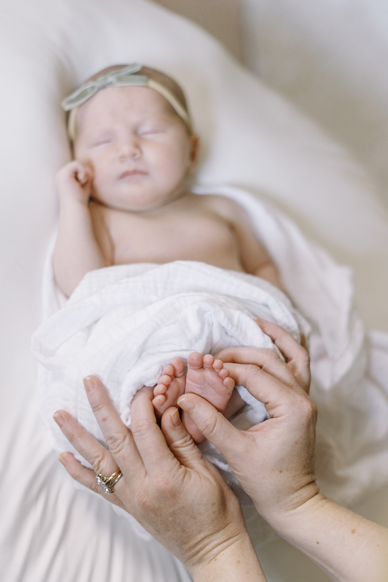 newborn baby feet with mother's hands