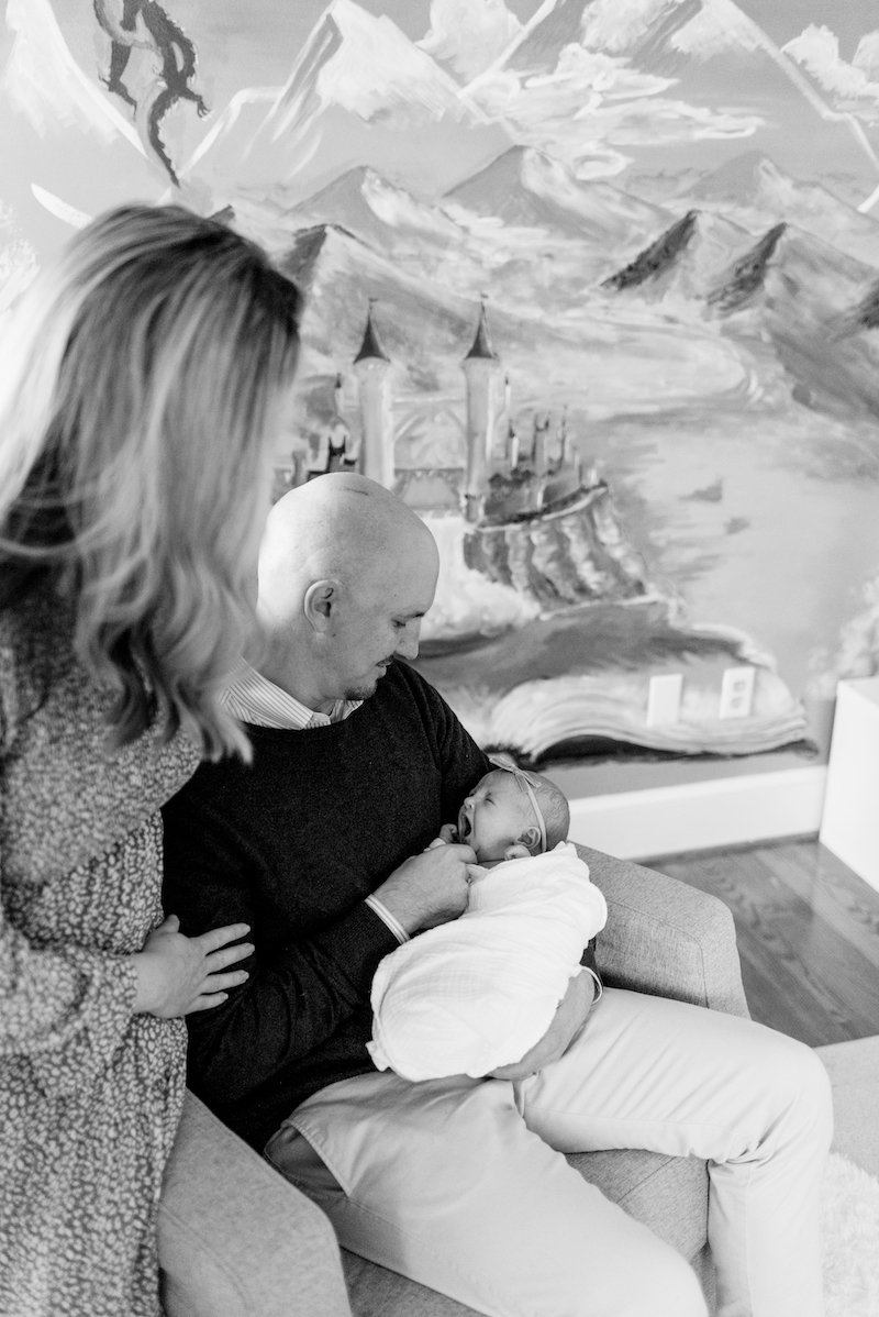 black and white  photo of parents holding baby in fairy-tale-themed nursery