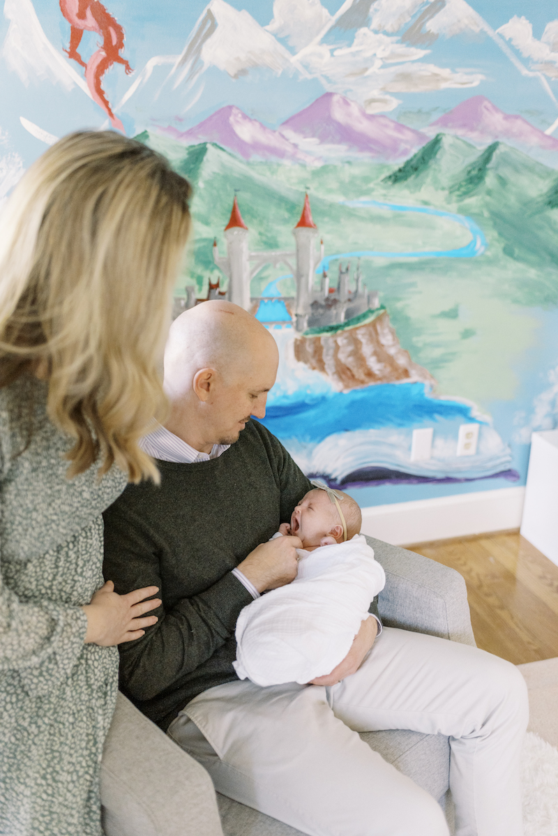 father and mother holding baby in fairy-tale-themed nursery