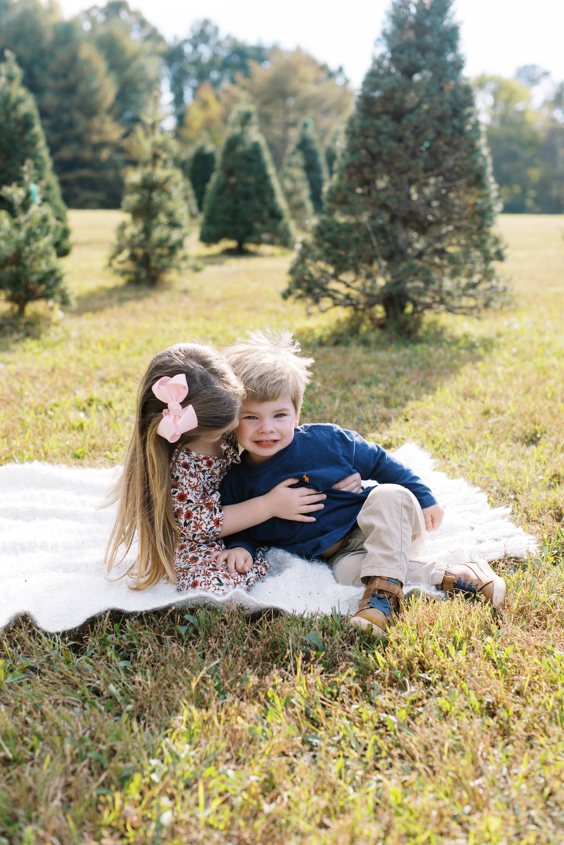 brother and sister hugging on blanket at christmas tree farm