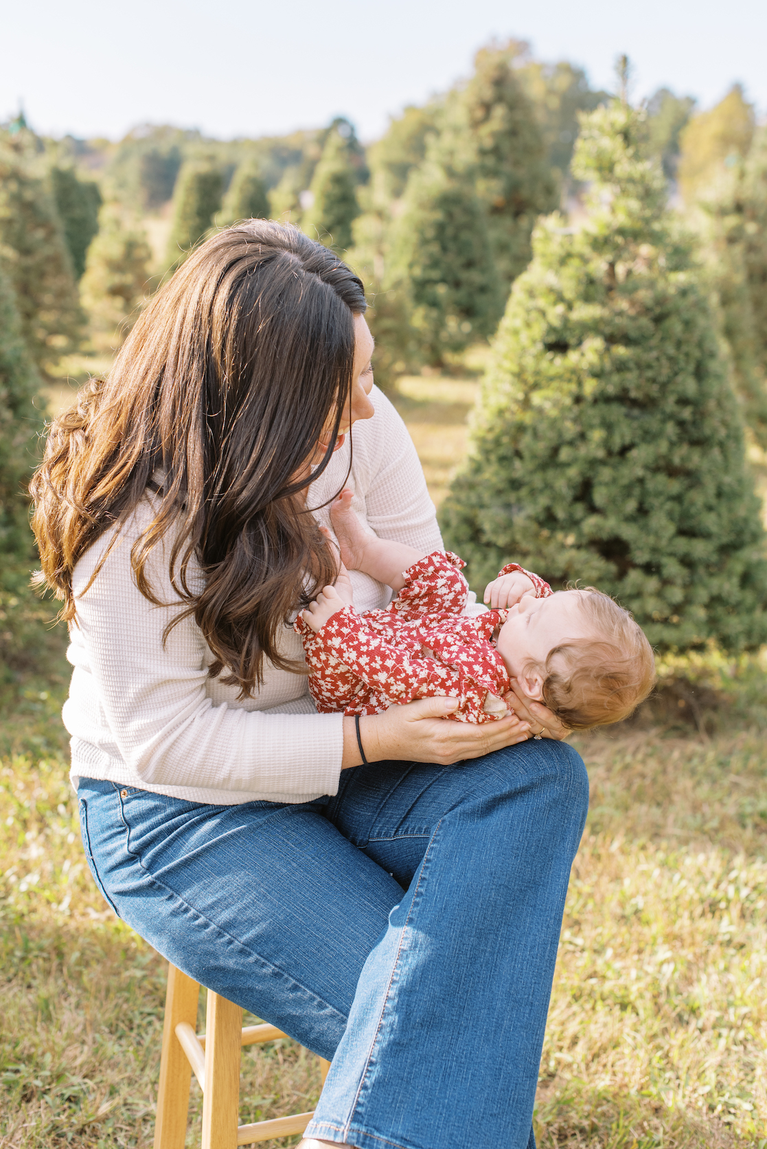 mother holding newborn for christmas card photo at christmas tree farm