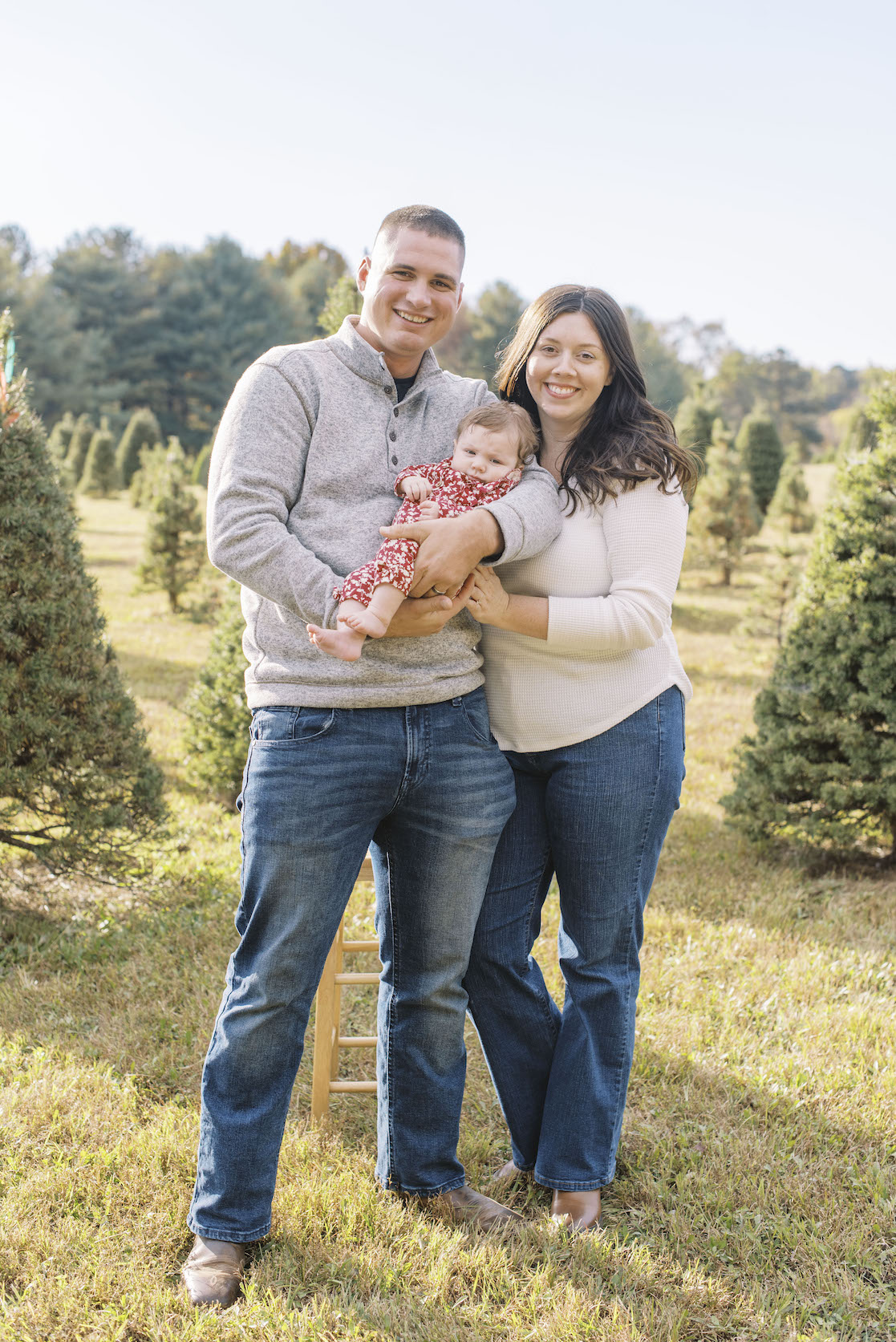 parents holding newborn for christmas card photo at christmas tree farm